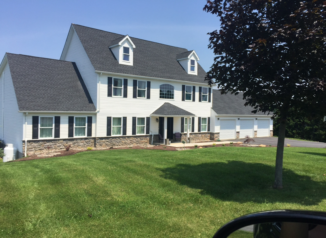Beautiful white colonial custom home with stone retaining wall and professional landscaping